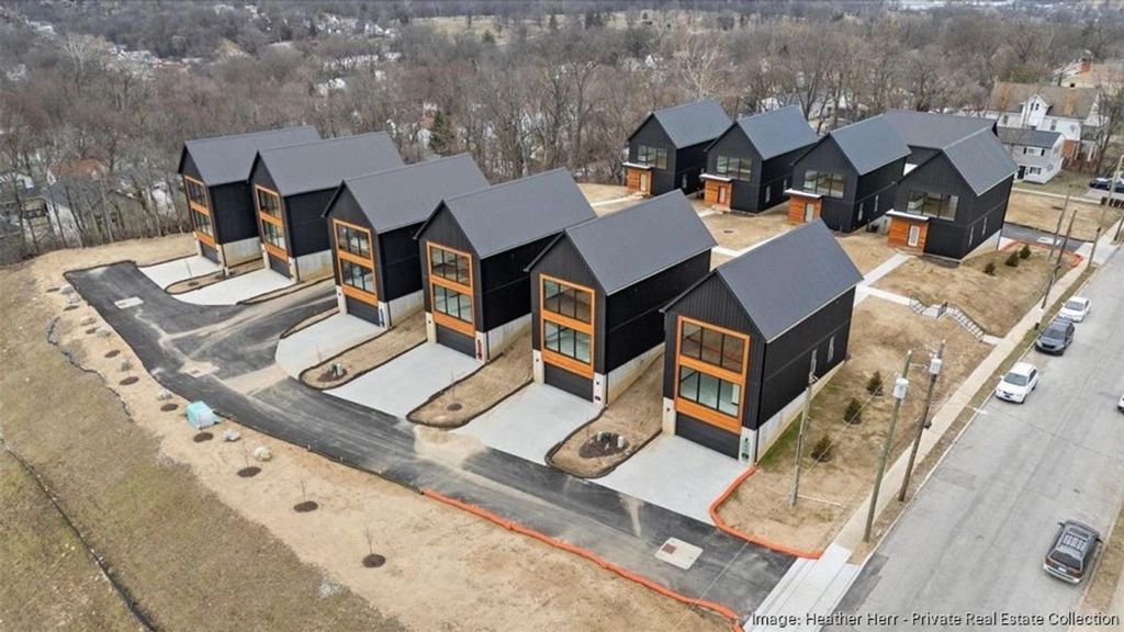 Modern black houses with large windows in a neat suburban layout.