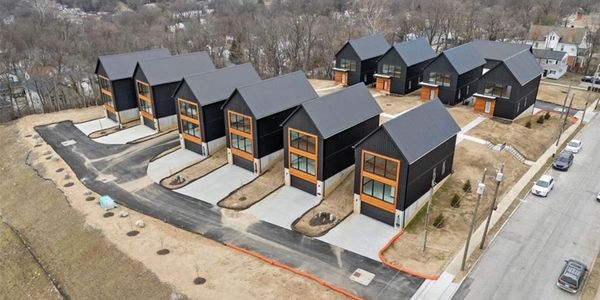 Modern black houses arranged in a neat row with driveways and minimal landscaping.