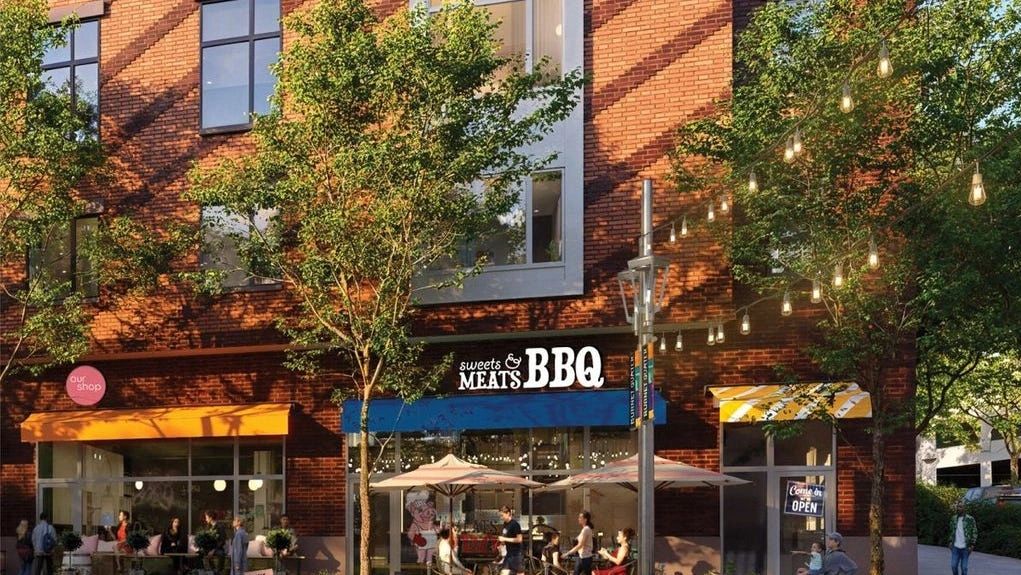 Outdoor seating area of a BBQ restaurant with trees and hanging lights.
