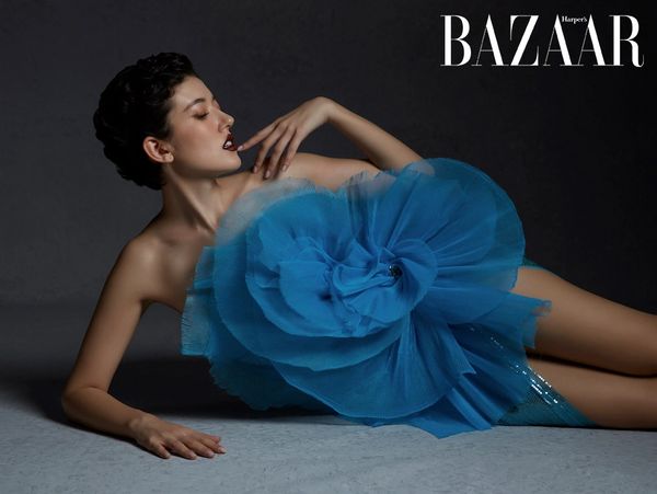 Model in a striking blue floral dress poses elegantly on the floor for Harper's Bazaar.