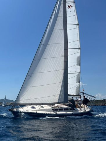 Sailboat with full sails gliding on blue water under clear sky.