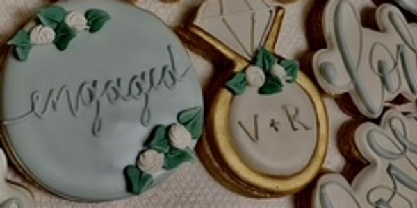 Decorative engagement-themed cookies with elegant script and floral accents.