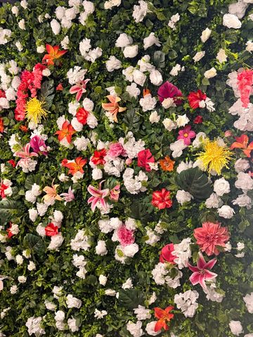 Wall covered with white and colorful flowers under a grey ceiling.