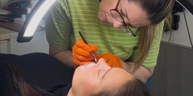 A professional applying eyelash extensions to a client under bright lighting.