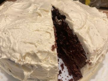 Chocolate cake with creamy white frosting and a slice cut out.