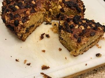 Sliced homemade cake with chocolate chips on a white cutting board.