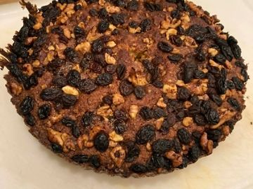 A homemade cake topped with raisins and walnuts.