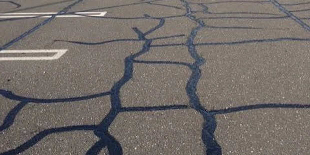 Cracked asphalt road with black sealant lines.