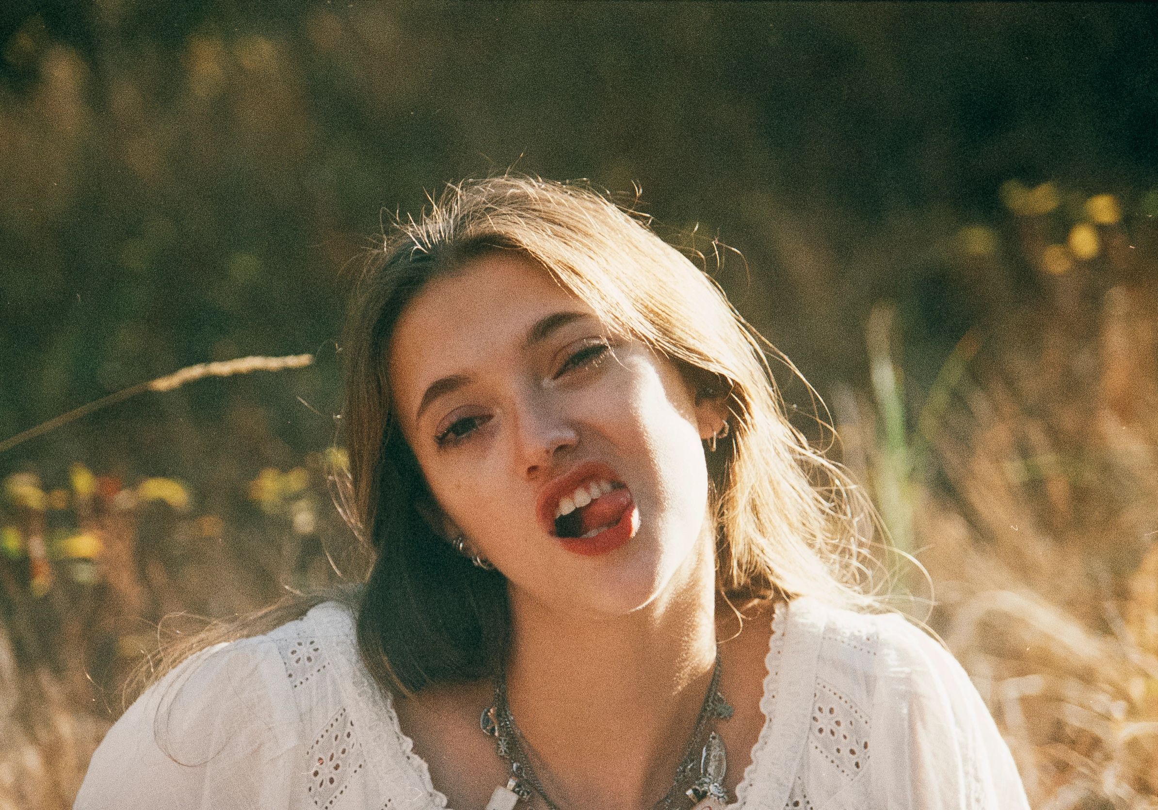 Young woman making a playful face outdoors in warm sunlight.