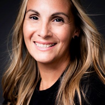 Smiling woman with long hair and a nose ring.