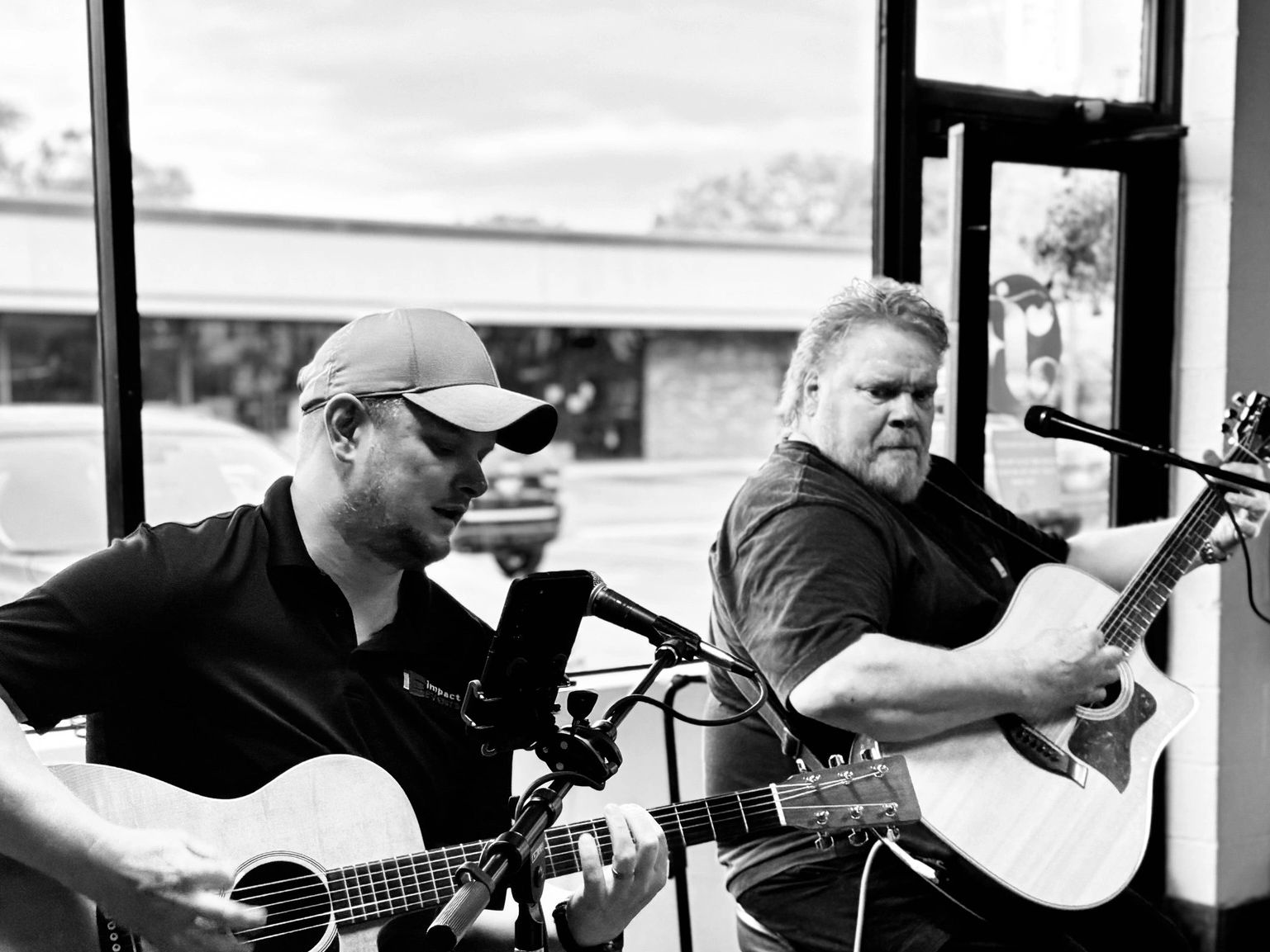 Two men playing acoustic guitars and singing indoors.