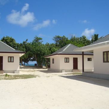 Small beachside bungalows under clear blue sky near the ocean.