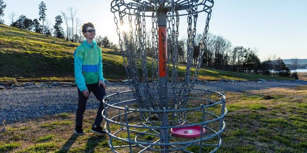 sunset approaches as disc lands in a disc golf basket