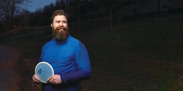 Man holds a disc golf driver ready to play at night