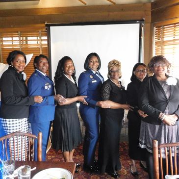 A group of women standing arm-in-arm indoors, smiling for a photo.