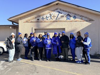 Group of people posing outside a building on a sunny day.