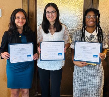 Three women proudly holding certificates of achievement.