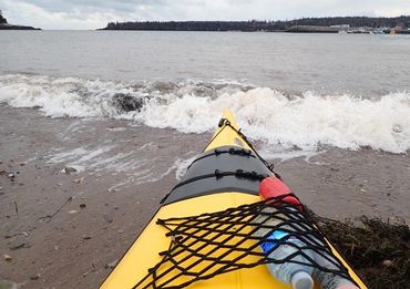 Sea kayak launching from the beach into a wave