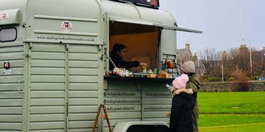 People order coffee from a mobile coffee trailer in a park.