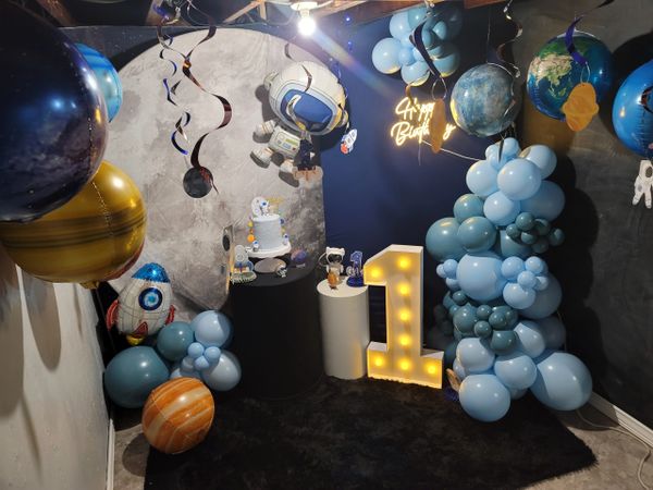 Space-themed first birthday party setup with balloons and decorations.