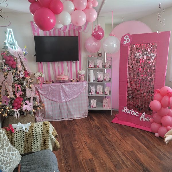 Pink-themed Barbie birthday party setup with balloons, cake, and decorations.