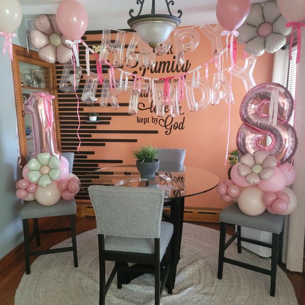 Pink and white balloon decorations celebrate an 18th birthday in a cozy dining room.