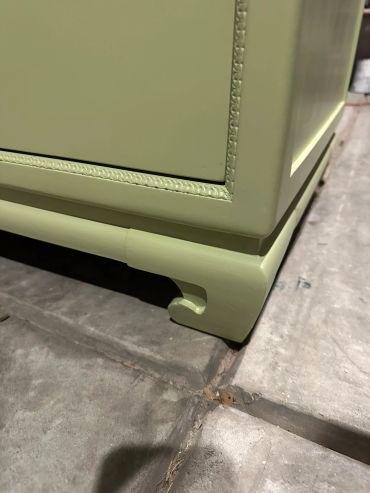 Close-up of green wooden furniture leg on tiled floor.