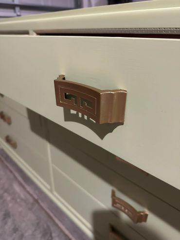 Close-up of a drawer handle on a white dresser.
