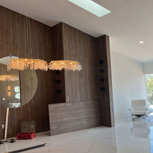 Modern room with wooden wall, crystal chandeliers, and a white chair.