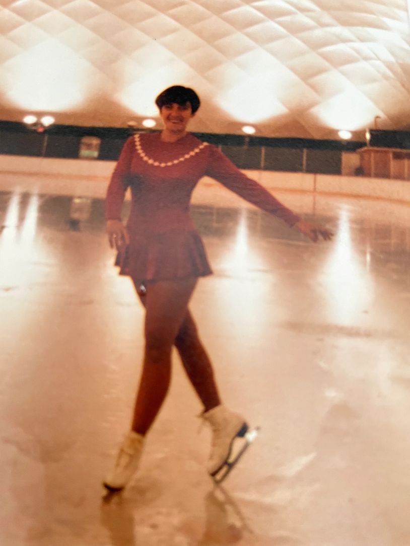Woman figure skating indoors on an ice rink.