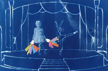 Child with paper flowers on a stage with a rabbit figure.