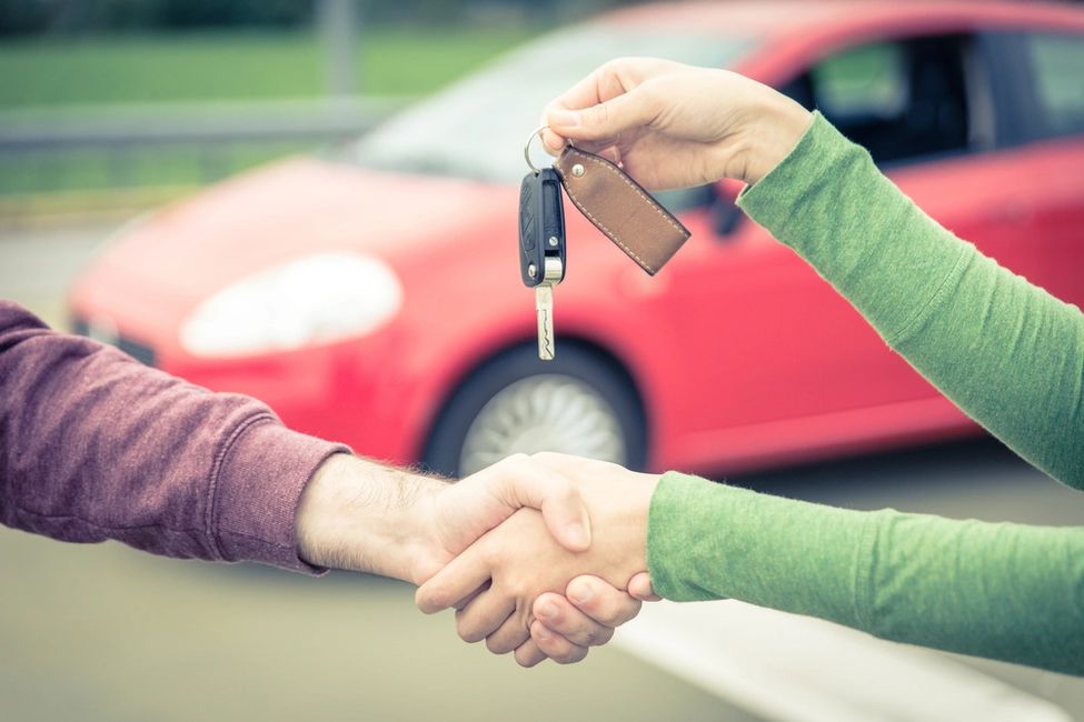 car sales buyer and seller get to an agreement handing over keys to new car bought from car dealer