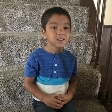 Boy sitting on stairs at home.