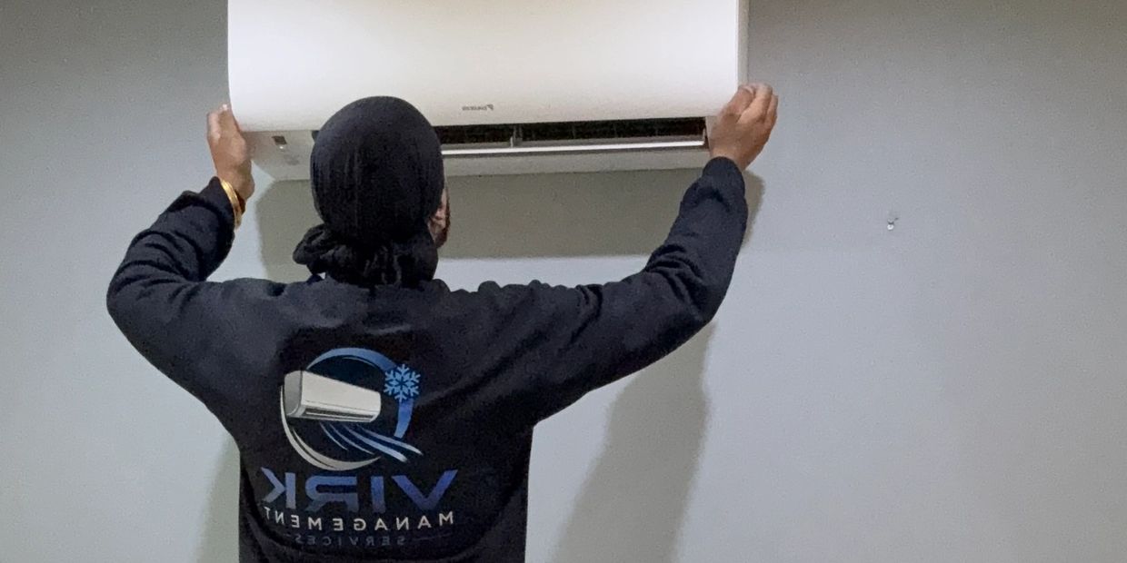 Technician adjusts wall-mounted air conditioner.