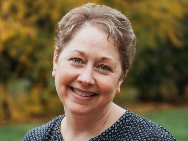Smiling woman with short hair standing outdoors in autumn.