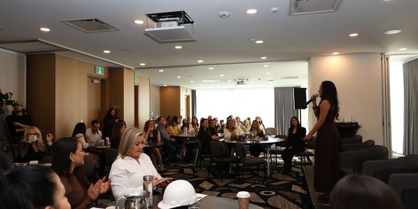 A woman speaks to an attentive audience in a modern conference room.