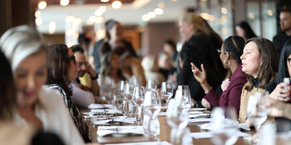 People engaged in conversation around a long dining table set for a meal.