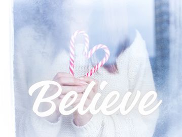 Person holding candy canes shaped like a heart behind a frosted window with 'Believe' text.