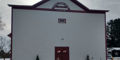 Large white building with red doors and a sign reading 'Sweet Steam House'.