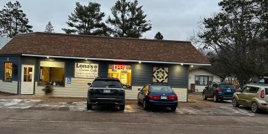 Exterior of Lorenz's Cheese Co. with parked cars in front under an overcast sky.