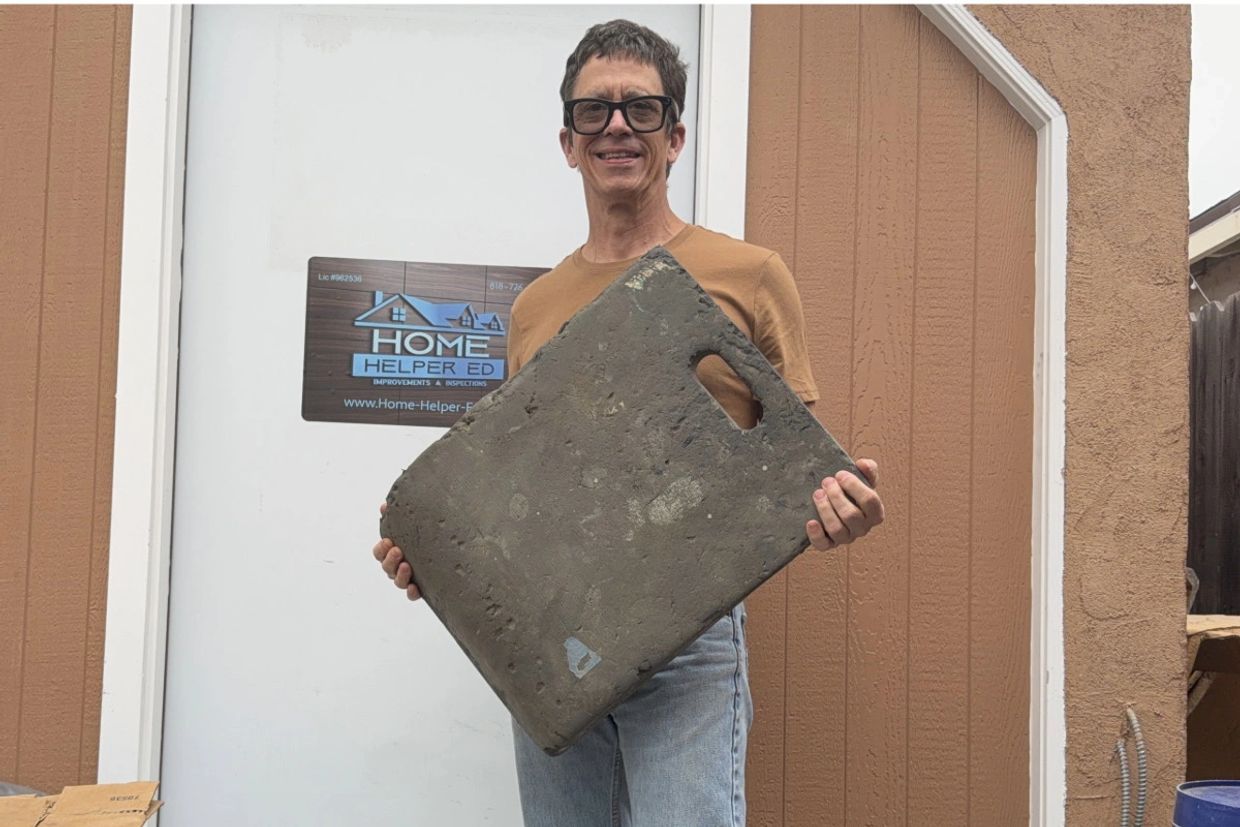Man holding a large, worn-out rectangular object with a handle.