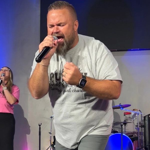 Man passionately singing into microphone on stage.