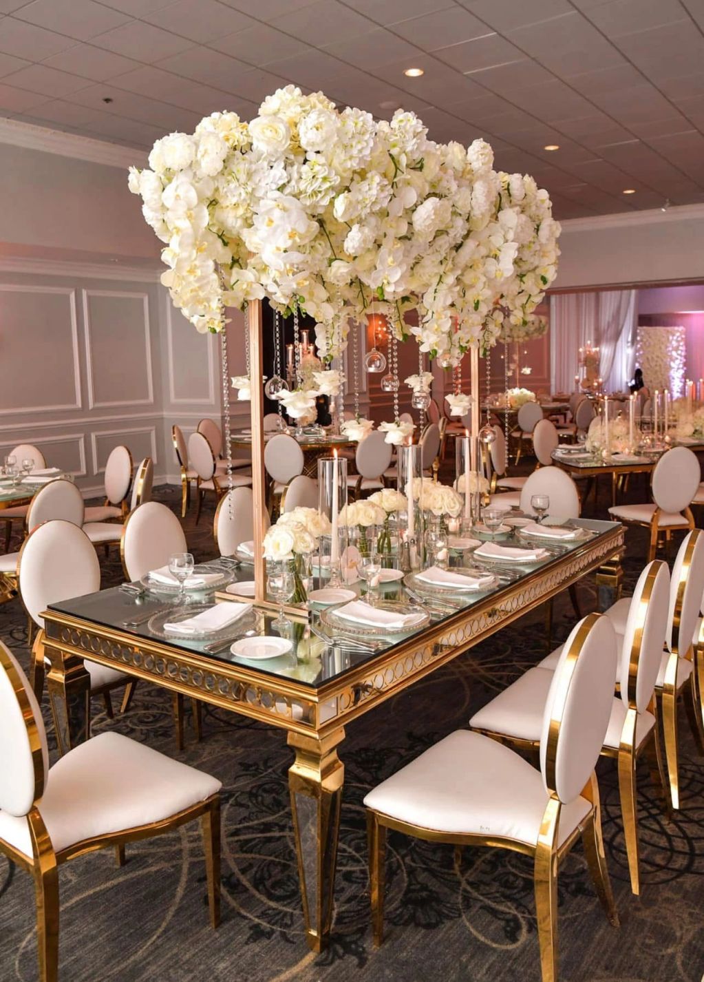 Elegant dining setup with gold and white floral centerpiece.