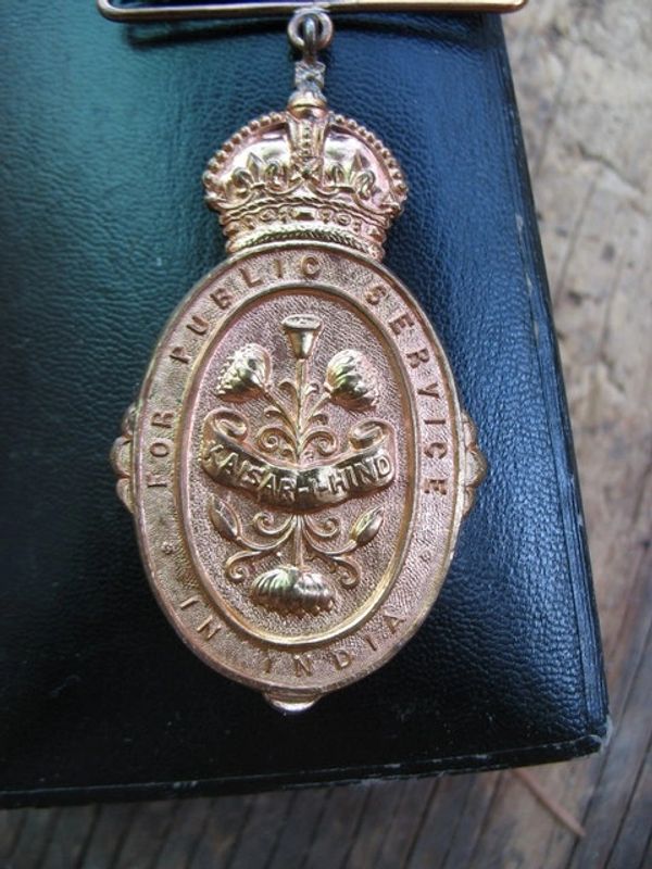 Close-up of a brass military badge with floral design and crown.