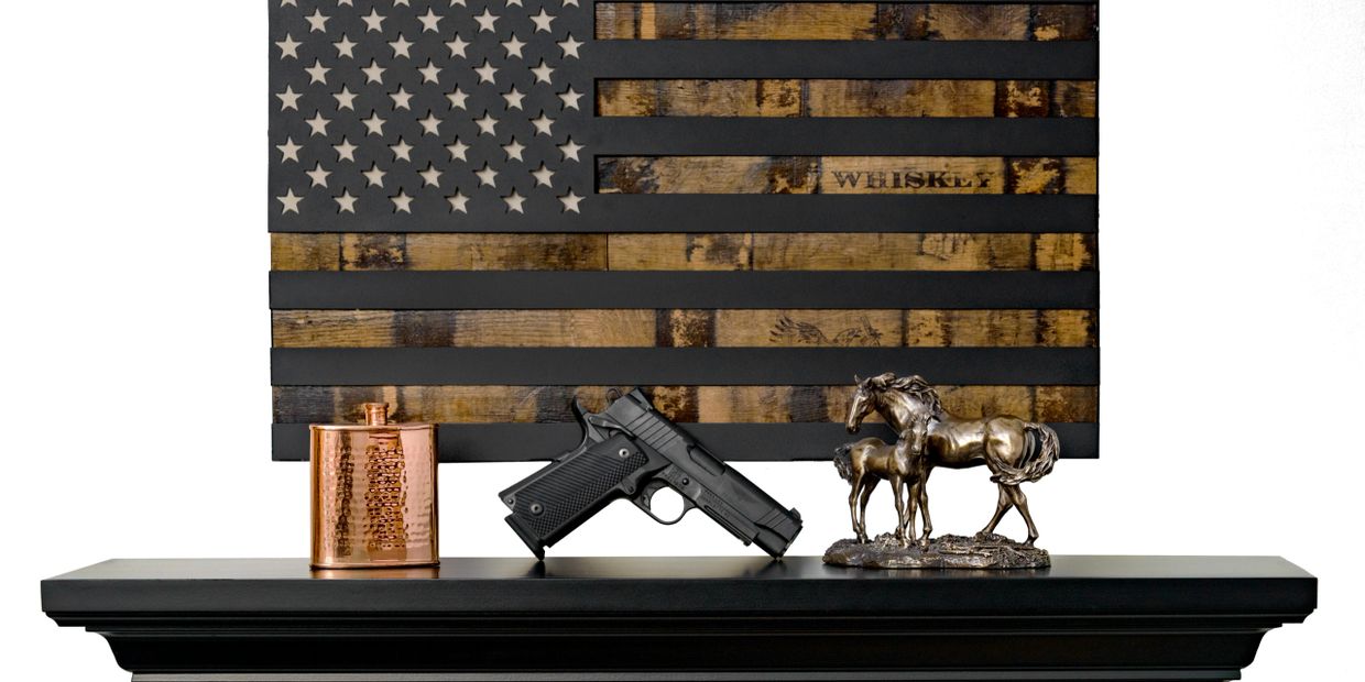 Rustic American flag wall art with a gun, flask, and horse statue on a black mantle.