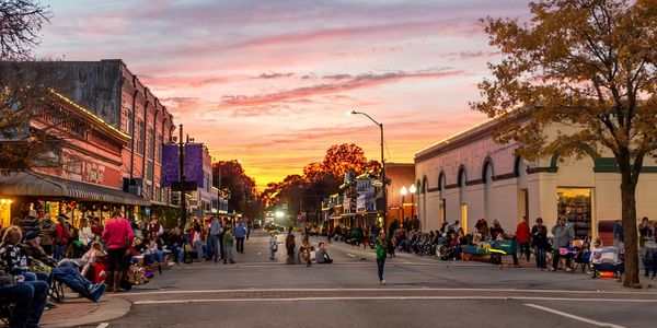 Crowd gathered on a street at sunset in a small town.