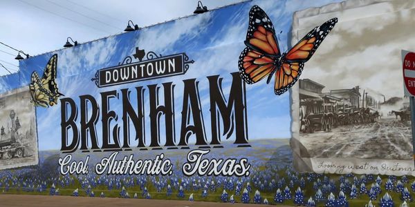 Mural in Brenham, Texas with butterflies and historical scenes.
