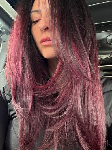 Woman with long vibrant pink-streaked hair indoors.