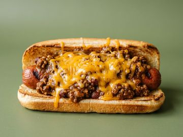 Chili cheese hot dog with melted cheddar on toasted bun.