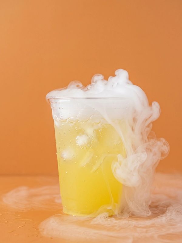 Yellow iced drink with smoky vapor against an orange backdrop.